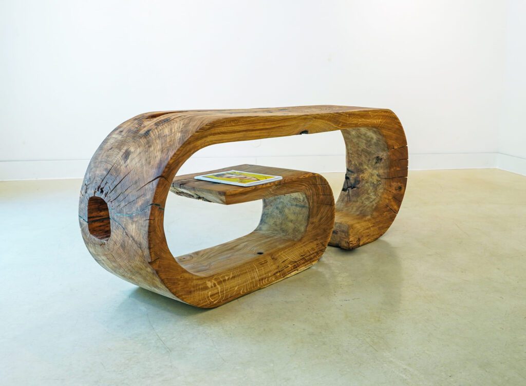 OZE sculptural wooden commode with floating shelf holding a tablet in a minimalist gallery setting